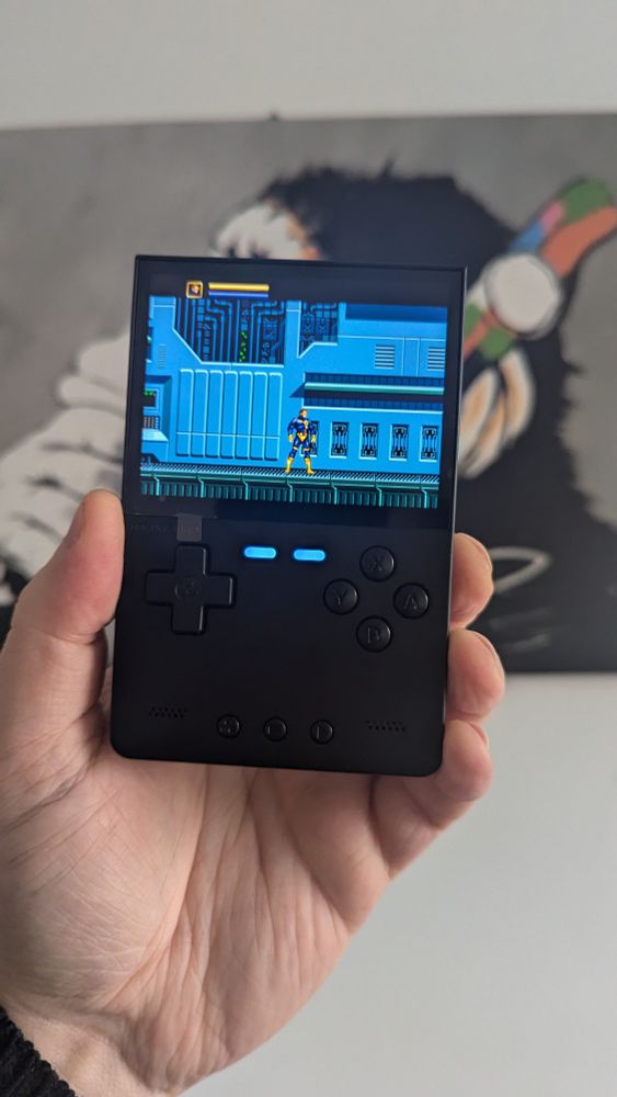 My hand holding the black TrimUI Brick playing X-Men for the Mega Drive. 