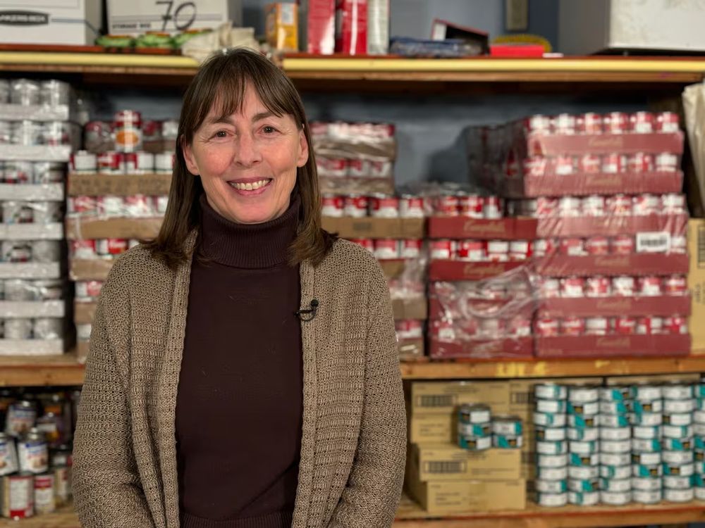 Woman poses in front of shelves of cans. 