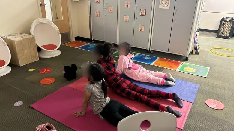 Children stretch on colourful yoga mats in a classroom.