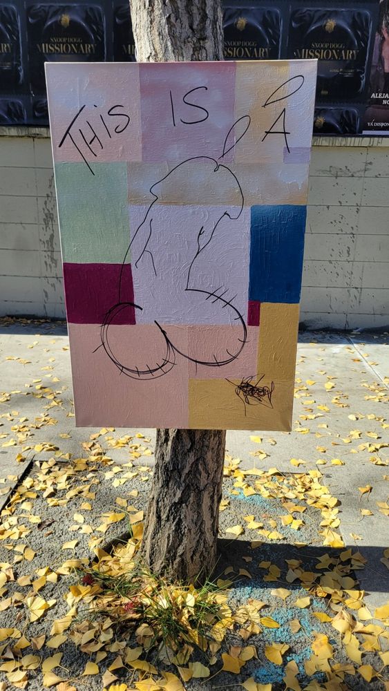 Street art reads "This is a", featuring a drawing of a penis, on canvas