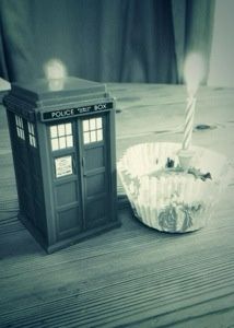 Tardis police box model and cup cake with birthday candle in sixties-era monochrome.