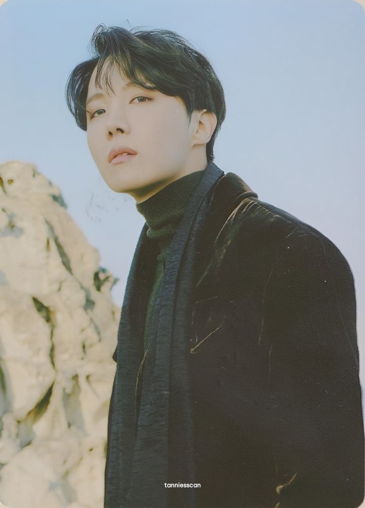 Winter package Hobi in all black standing on a cliff and looking wistfully at the camera 