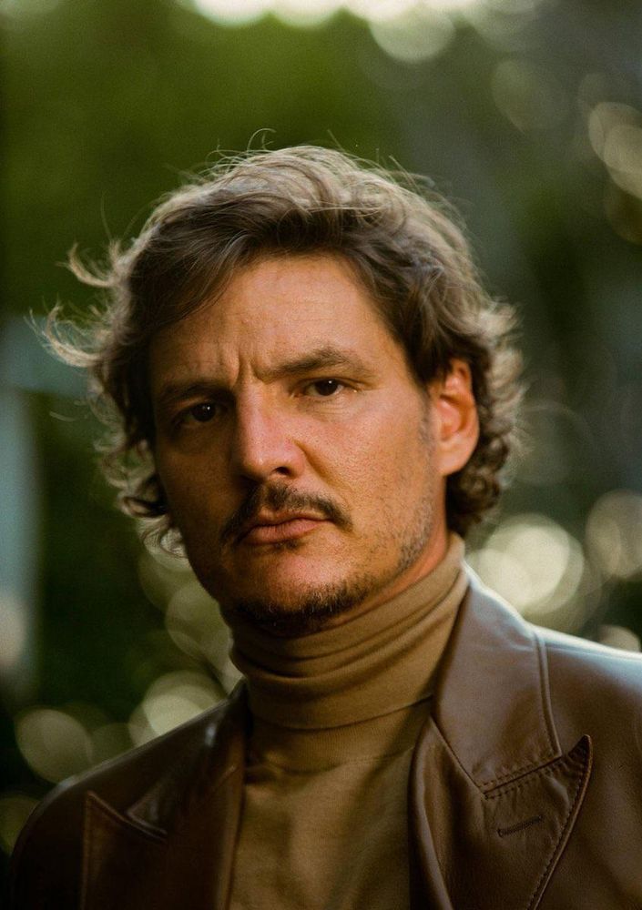 Pedro Pascal in an olive turtleneck and a brown leather jacket and stubble, very nice