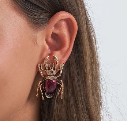 very big earring in the form of a stag beetle. it's the size of the wearers ear. It's gold with rhinestones and the body is one big red stone. with its legs it does look a bit like a spider on a glance. It's definitely not going unnoticed if you wear it!