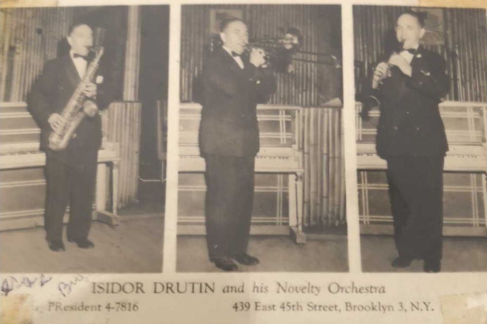 photo of an old business calling card with three photos of a man playing saxophone, trombone and clarinet. It says ISIDOR DRUTIN and his Novelty Orchestra with a phone number and address in Brooklyn.