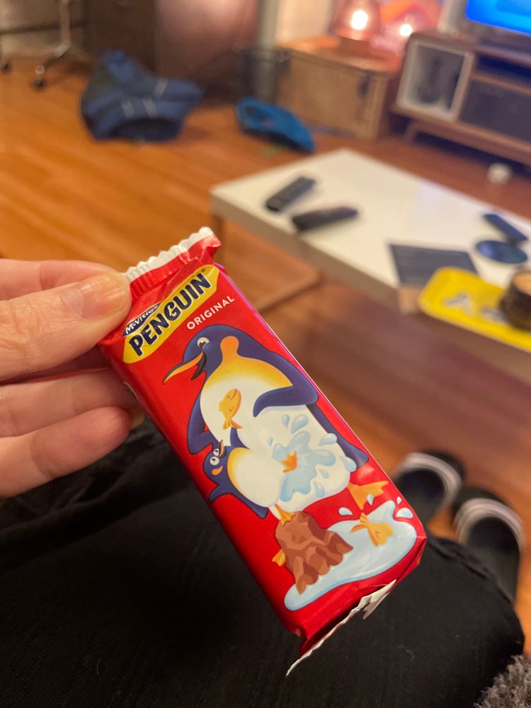 Chocolate penguin biscuit shown in its wrapper. The penguin appears to be swimming