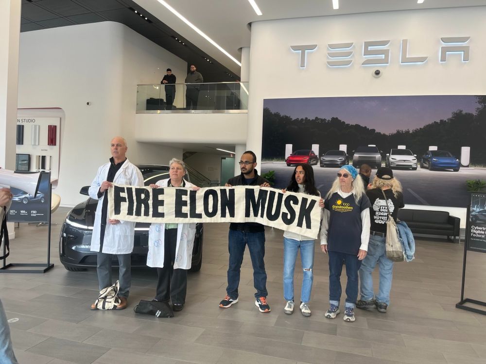 Fire Elon Musk protestors hold banner inside Tesla showroom in San Francisco