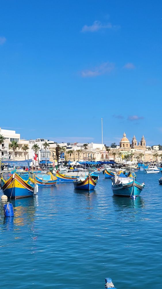 Marsaxlokk Harbour, with colourful luzzu boats on clear blue water