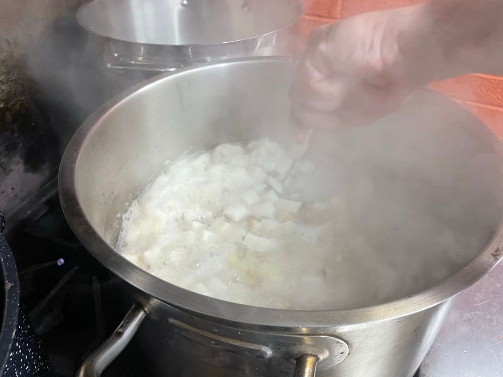 Stirring a pot of boiling potatoes and turnips.