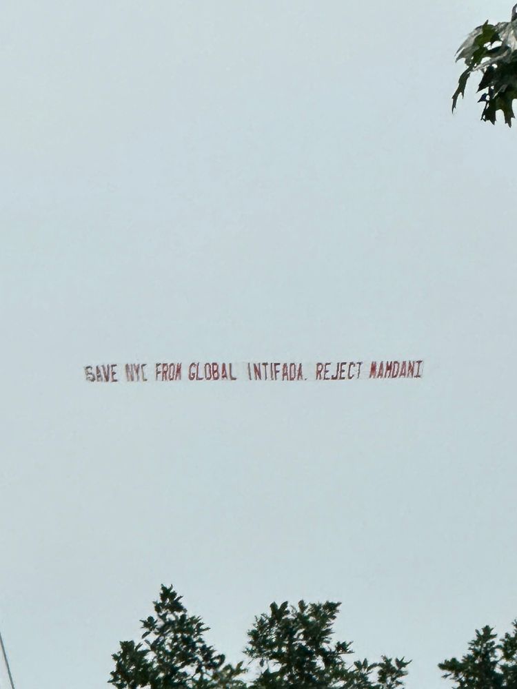 A flag in the sky says save n y c from global intifada. Reject Mamdani