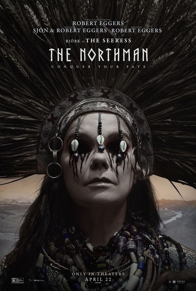 A poster for The Northman.  It shows Björk as a seer, wearing a wheat headdress and a huge pile of beaded necklaces. Cowrie shells hang covering her eyes, which are bleeding.