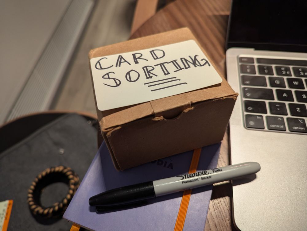 A Sharpie, a notebook and an index card that reads 'card sorting'