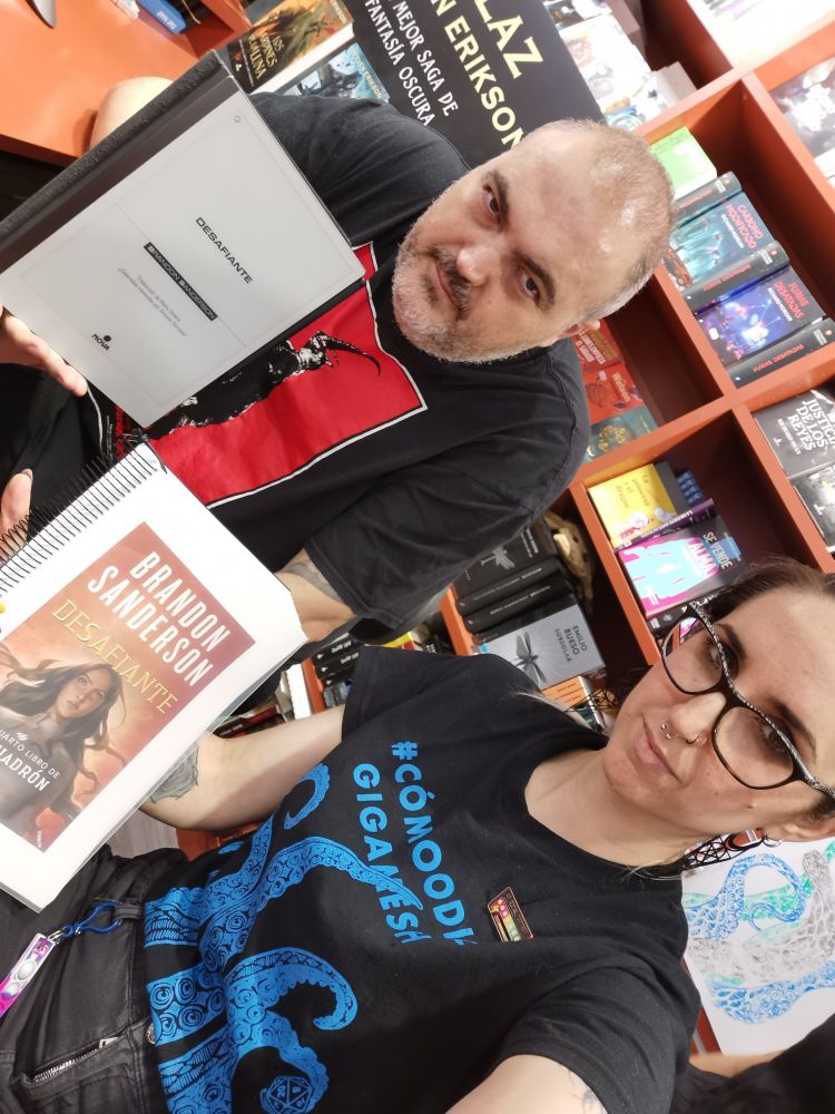 @toliol (Antonio Torrubia) y Alba Herre, ambos libreros de Gigamesh, enseñando Desafiante, de Brandon Sanderson, Antonio en digital y Alba encuadernada.