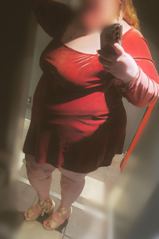 Tall blonde BBW in avery short, long sleeved red velvet dress, she poses in golden silk heels.
