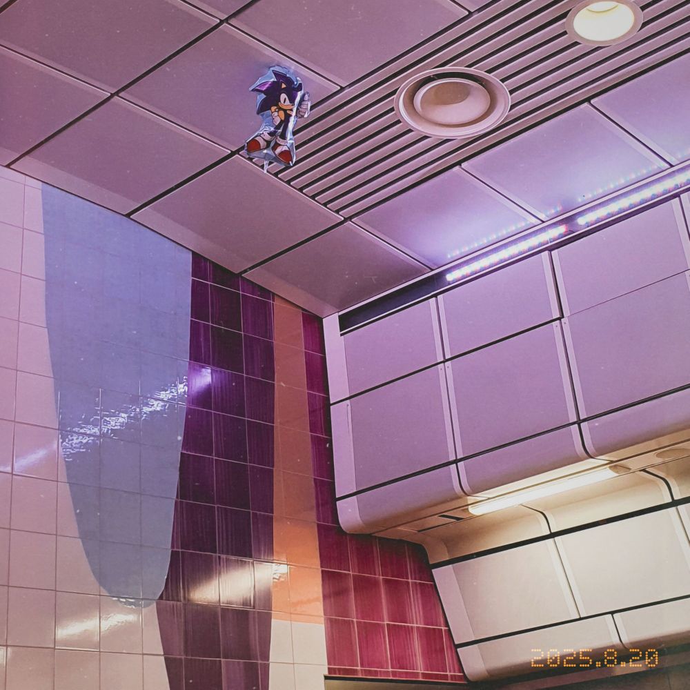 Photo of a single sonic balloon, stuck at the ceiling at the commuter train platform at stockholm central station. Still doing his thumbs up pose, almost mockingly. Why are you so positive sonic?! 