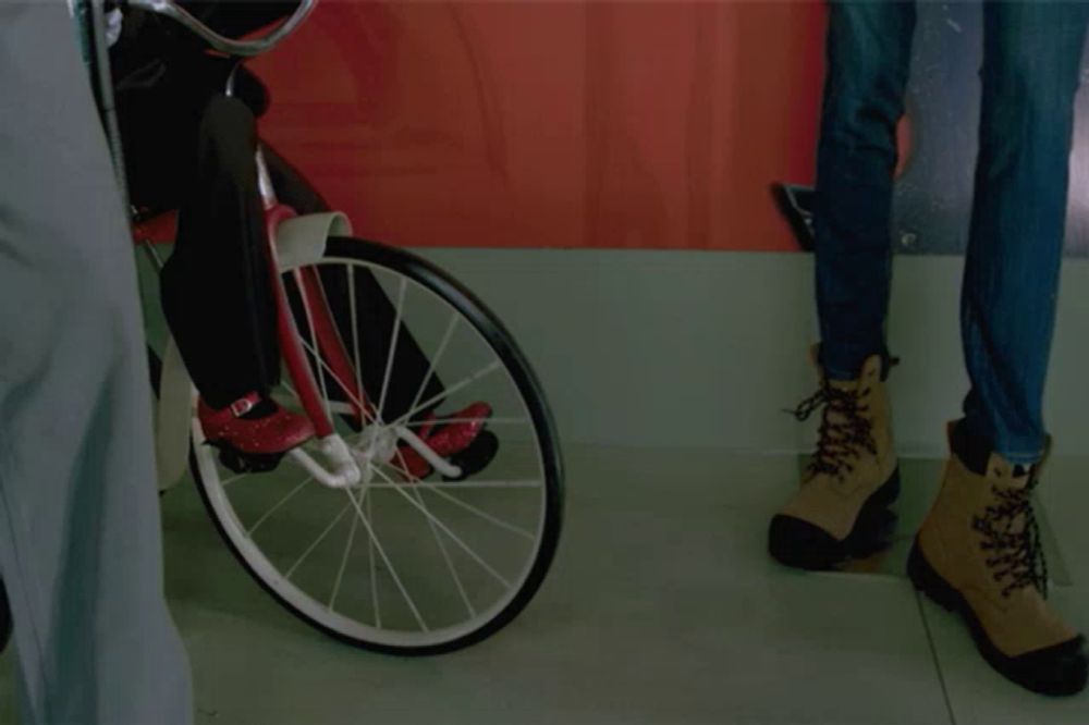 a puppet is riding a bike next to a woman 's jeans