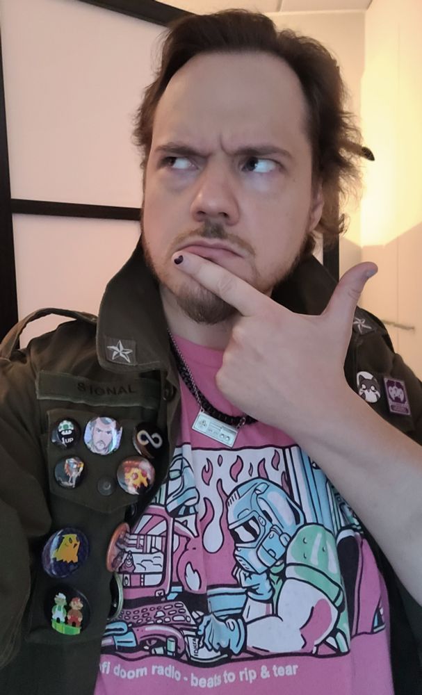 Man in green jacket and pink shirt featuring Doom the video game looking up and pondering.