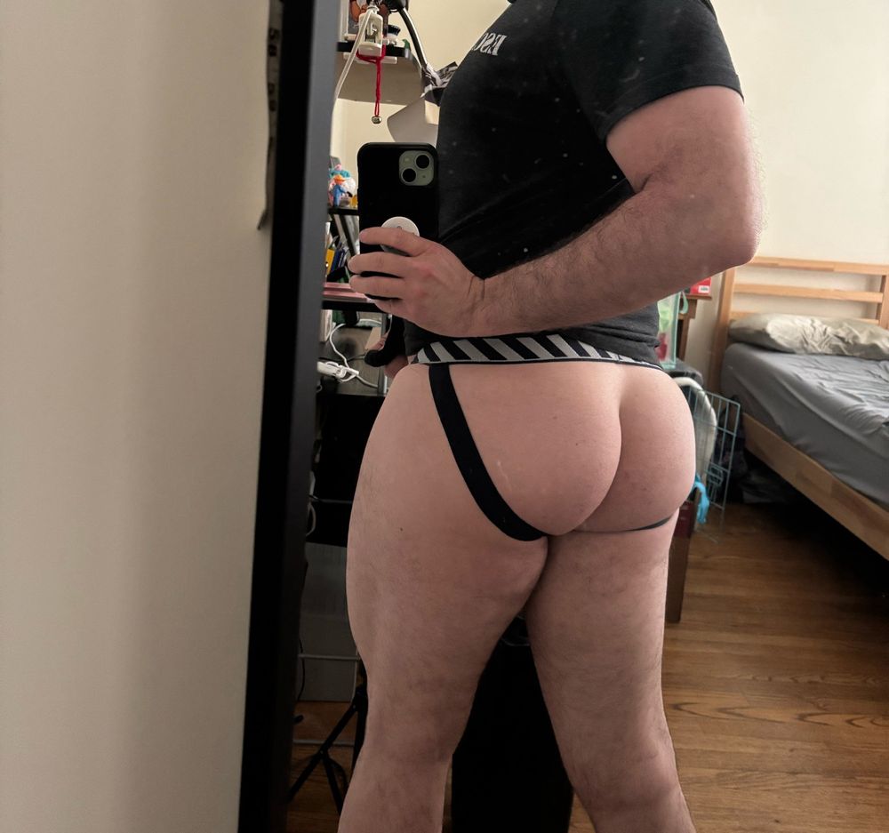 Mirror selfie of a man’s mid section turned around to show off his big bubble butt in a jockstrap and strong quads