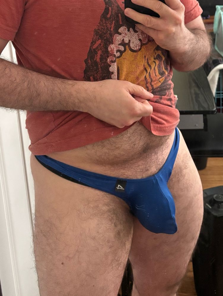 Bulge picture with the front of my shirt lifted up to expose a well defined cage bulge in blue poser style thong with excess fabric bunched at the front 