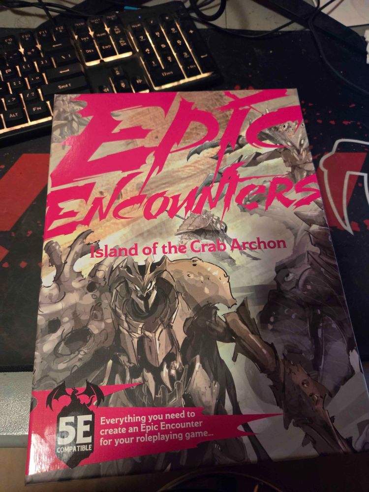 Photograph of a large box of miniatures from Steamforged Games' Epic Encounters line of products. It says "Island of the Crab Archon" on it, and has a large crab-like humanoid on the lid.