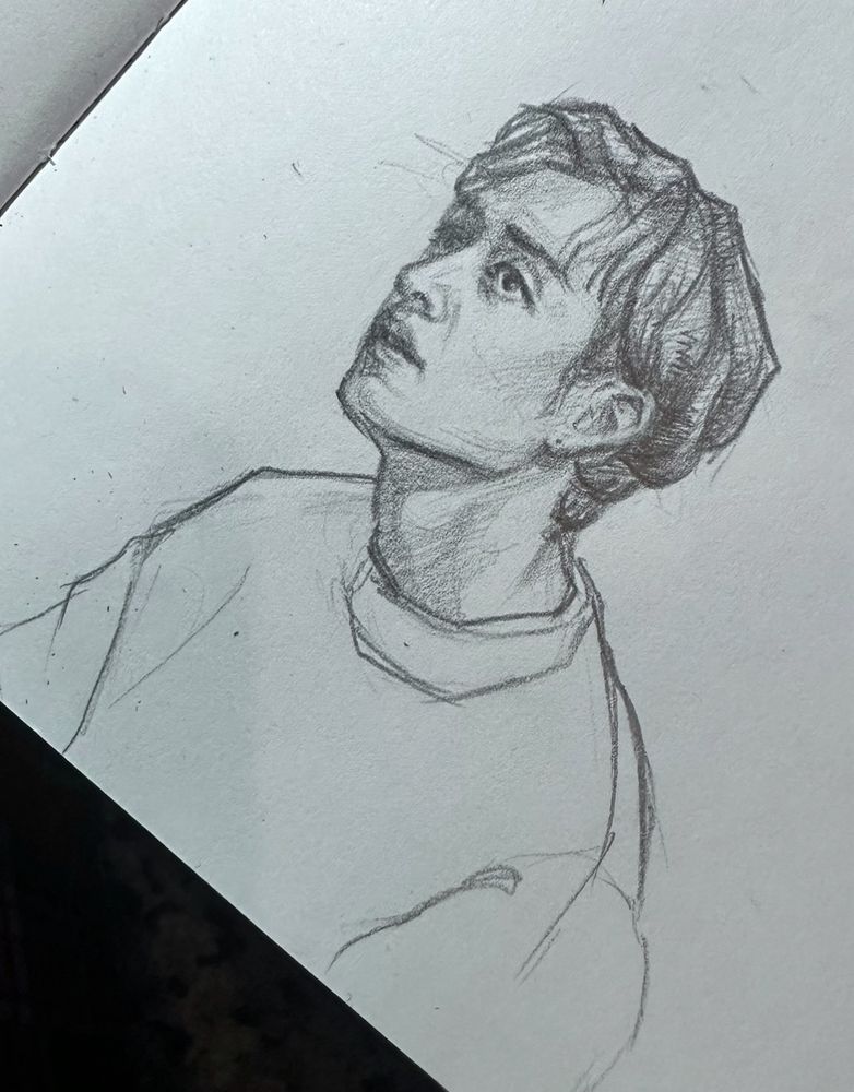 a pencil sketch of Bang Chan from the band Stray Kids. It’s a three-quarters portrait, Bang Chan is facing left and slightly looking upwards