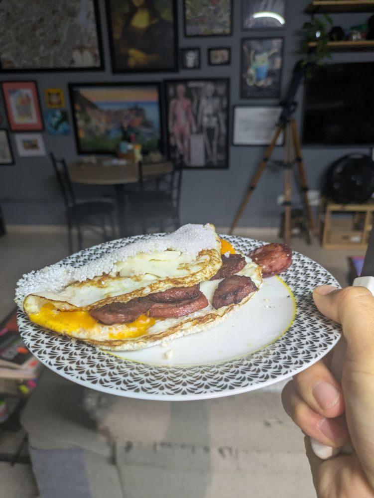 Um prato com uma tapioca recheada com 2 ovos, queijo e calabresa
