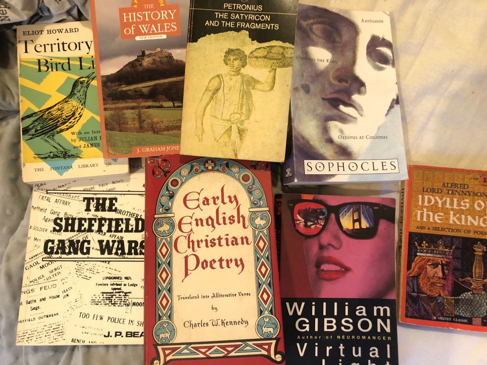 a pile of used books - territory in bird life by eliot howard, a pocket guide to the history of wales by j graham jones, petronius’ the satyricon and fragments translated by j.p sullivan, sophocles from QPB classics, the sheffield gang wars by j.p bean, early english christian poetry, translated by charles w. kennedy, virtual light by william gibson, and tennyson’s idylls of the king