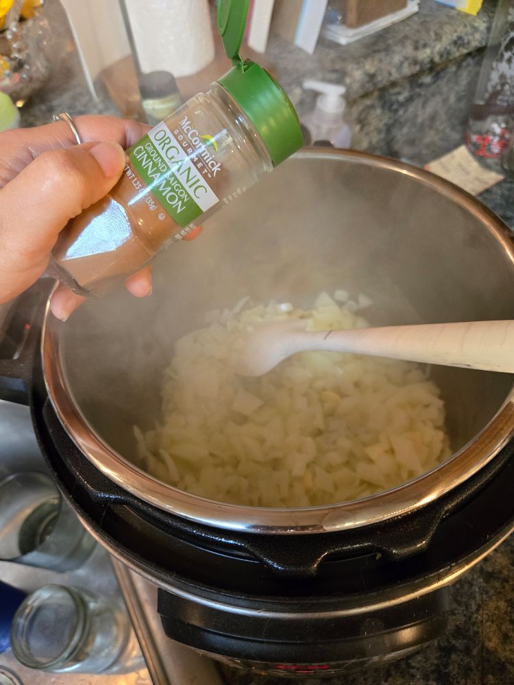 Putting some cinnamon in a pot of sauteeing onions