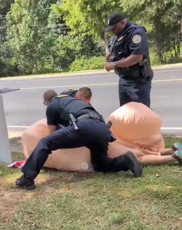 Police in Georgia arresting a woman in a cartoonish blowup penis costume add a no Kings rally because public ludeity. 