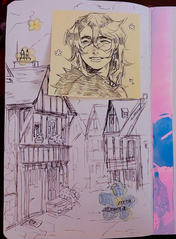Recent traditional art of a town drawn in a fountain pen in a sketchbook. There is another fountain pen doodle of a portrait of a   freckled man with long hair smiling on a sticky note over the drawing of the buildings. 