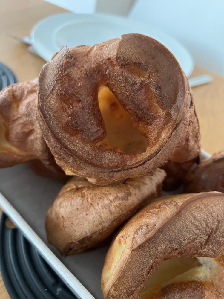A serving dish full of Yorkshire puddings.