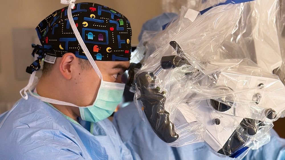 John Yue, MD, looks through a microscope during a pituitary tumor resection.