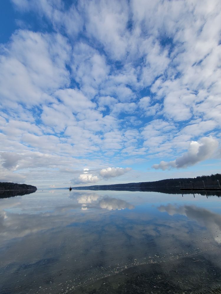 Calm bay water reflection of clouds and sky