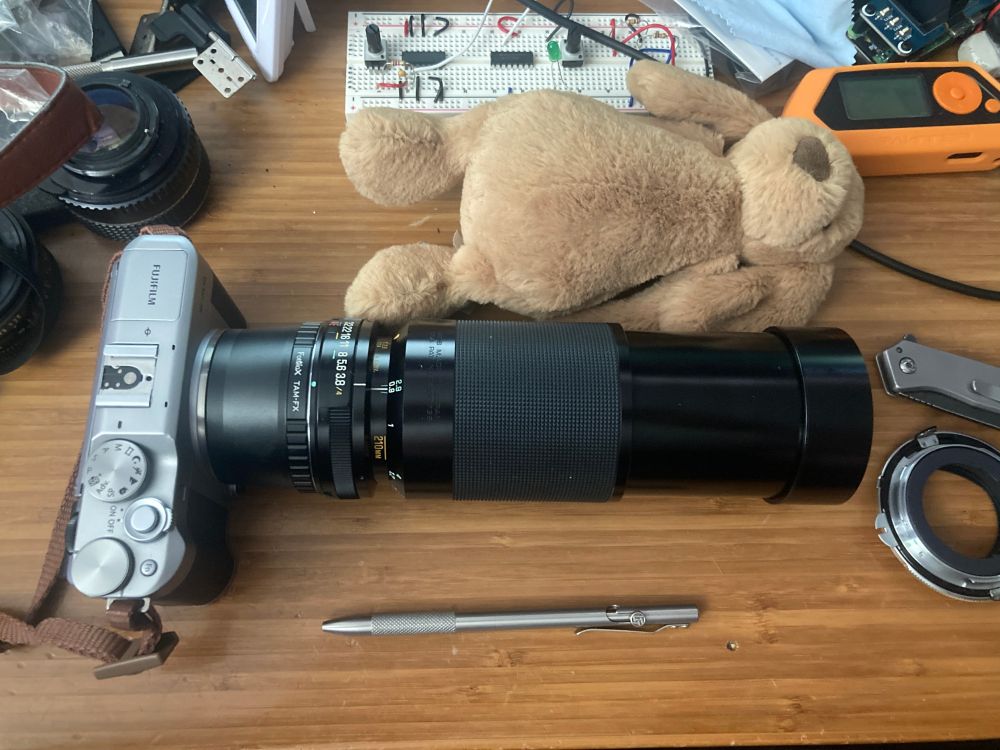 A 7 inch long camera lens, attached to a 1.5 inch long adapter, attached to a 1.25 inch thick camera.