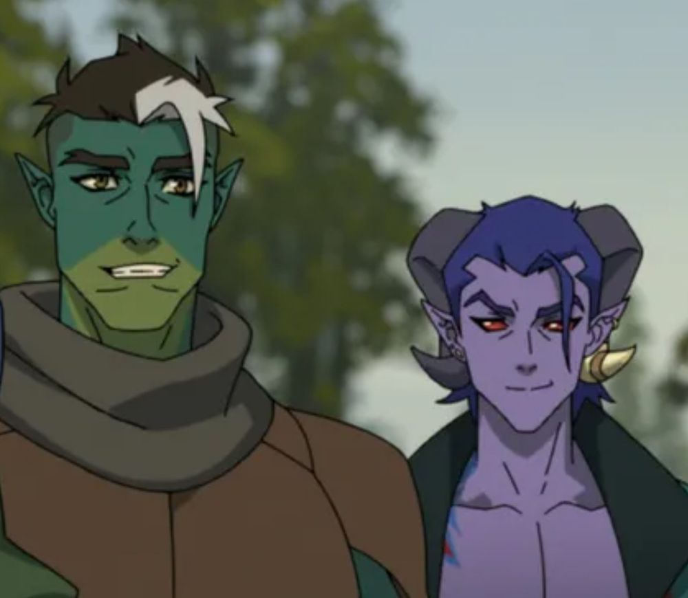 Screenshot of two characters from the mighty nein animated series: left is a tall green man with pointed ears and short black hair with a white streak while the right is a purple man with curled horns, red eyes, and an extreme deep v jacket. You can see a little bit of a hint of a tattoo on his right shoulder