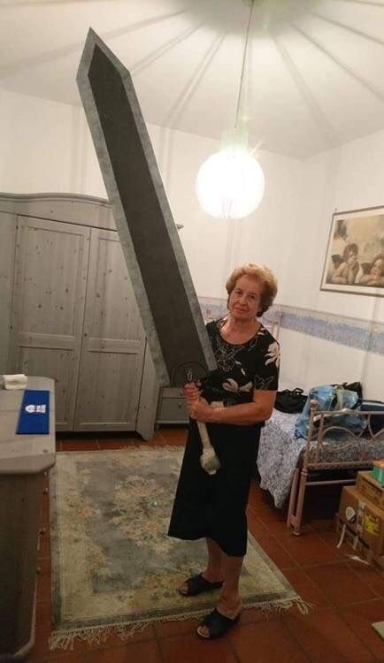 Old lady holding a giant prop cardboard sword