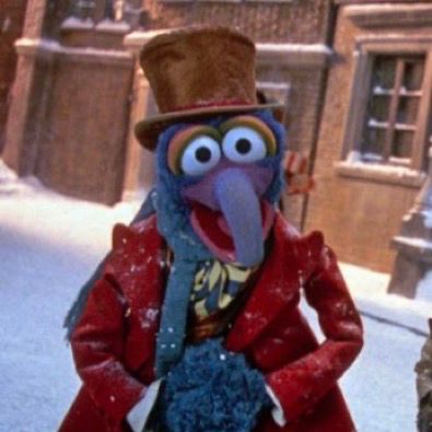Wonderful iconic legend Gonzo the Great in A Muppet Christmas story, ALSO wearing a brown top hat, a red overcoat, and a multicolored scarf and vest. he is clearly wearing it better 