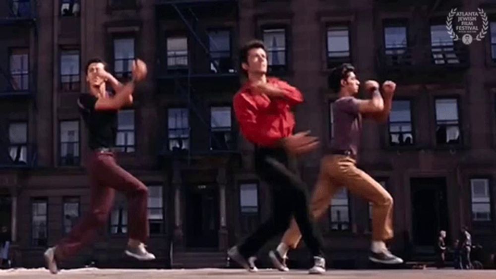 three young men are dancing in front of a building .