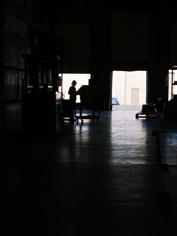 Photo, unedited. Silhouette, glare, and reflections, open warehouse doors on a sunny day.