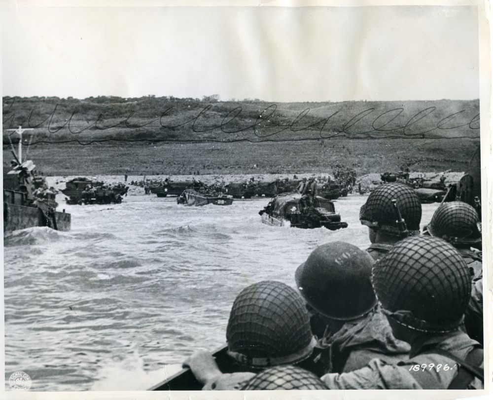 Photo Courtesy of the National Archives.

Original Caption: "Vast numbers of troops leave "dukws" and other landing craft onto the Continent, at Omaha Beach, France. Soldiers on left are ready to leap into the surf."

NAID: 176887788
