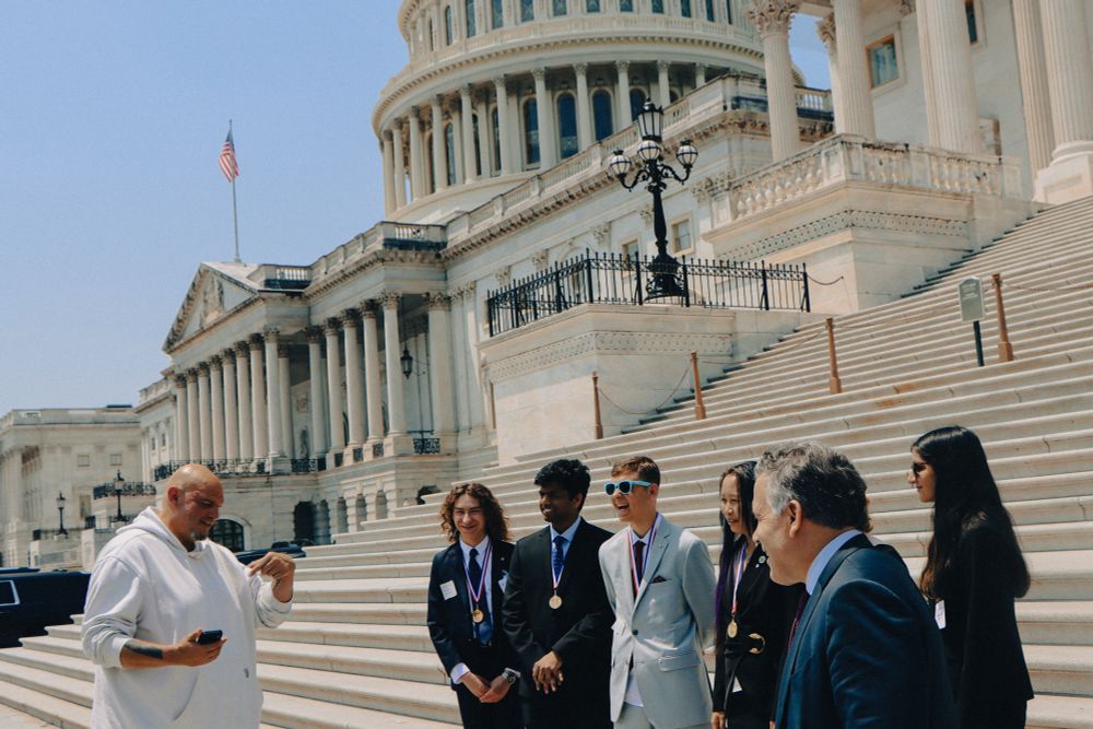Senators Fetterman and McCormick talking with the six gold medalists in front of the Capitol building.