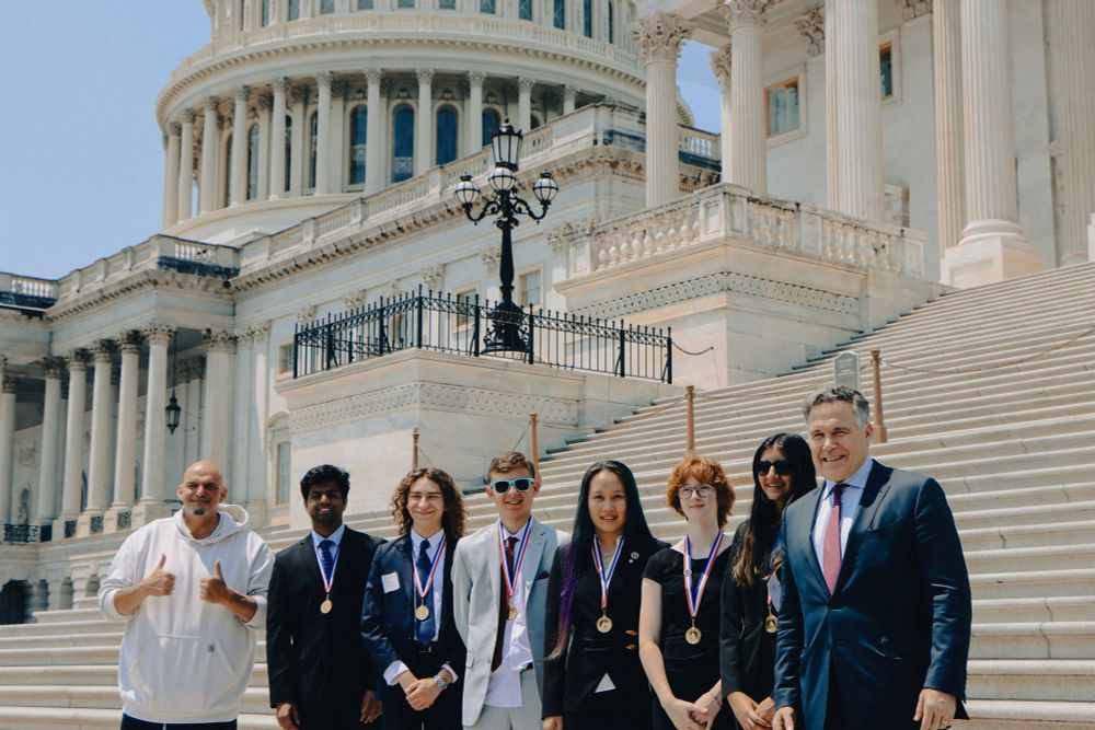 Senators Fetterman and McCormick taking a group picture with the six gold medalists in front of the Capitol building.