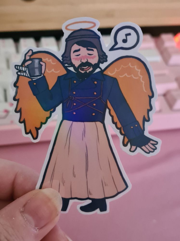 between thumb and finger is held a sticker of character irving from amc's the terror, wearing his carnivale costume in which he wears gold angel wings and a halo. he's raising a steel cup in a bandaged hand. a single music note is in a speech bubble near his head.