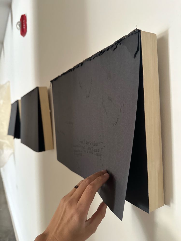 Black construction paper pad with a hand holding one sheet