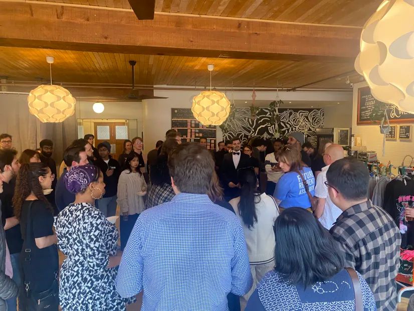 A packed room of people gathered around Zak, a board member of MNTO.