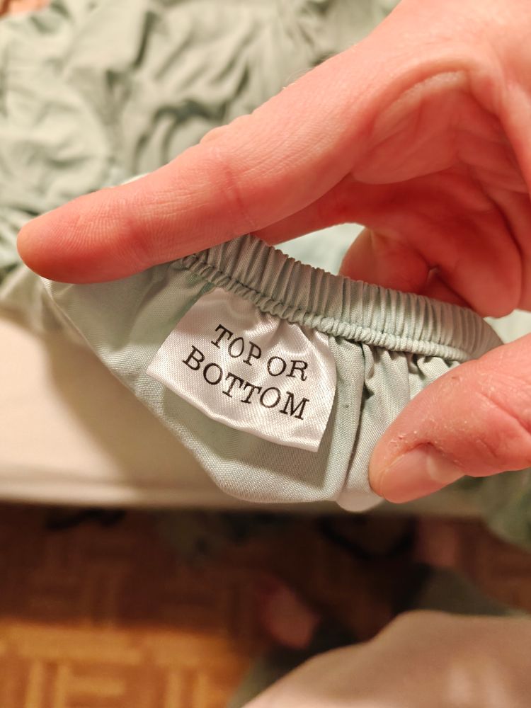 fitted sheet with a tag that reads "TOP OR BOTTOM" in all caps