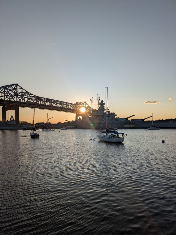 The sun behind the Braga Bridge and Battleship Massachusetts