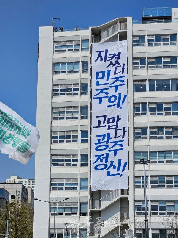 2025년 4월 4일 윤석열 파면 직후 공개된 "지켰다 민주주의! 고맙다 광주정신!"이라는 문구가 쓰여진 전일빌딩 벽면에 달린 현수막. 그 왼쪽에는 윤석열죽각퇴진・사회대개혁 비상행동(현재 내란청산・사회대개혁 비상행동)의 깃발이 있다.