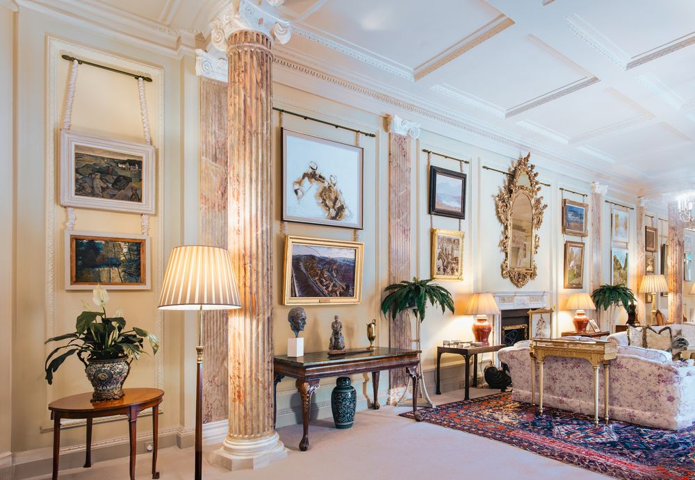 Interior photo of a brightly-lit drawing room with paintings hanging on the wall.