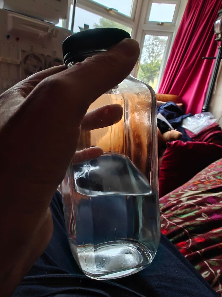 A photo of a small bottle of water, half empty 